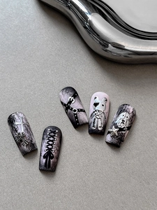Close-up of gothic Y2K press-on nails with silver metallic charms and cross accents