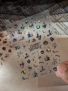 Macro detail of holographic Halloween nail stickers with pumpkin and ghost motifs