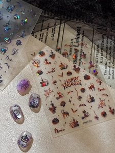 Macro shot of holographic Halloween nail stickers with pumpkins, bats, and spiders