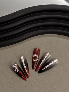 Macro shot of 3D bone and blood splatter details on dark red Halloween press-on nails