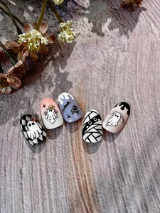 Detail of Halloween press-on nails featuring ghosts and mummies on wooden background