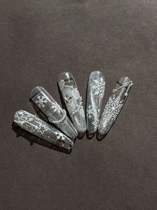 Detail of silver glitter coffin press-on nails with 3D white snowflakes and pearls