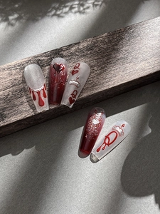 Detailed view of dark gothic press-on nails with wine red hearts and crown designs