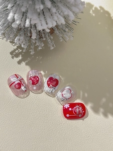 Détail de stickers à ongles de Noël avec nœuds 3D et motifs festifs sur base rouge