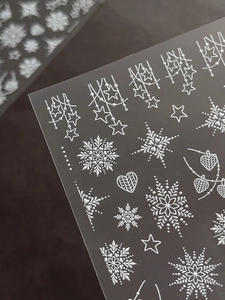 Macro detail of 5D embossed white snowflake nail stickers with 3D star textures