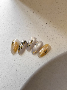 Vista macro di nail art in stile cinese con fiori di osmanto, calligrafia ed effetto occhi di gatto