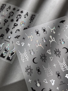 Macro shot of Halloween nail stickers featuring spiders ghosts and holographic glitter details