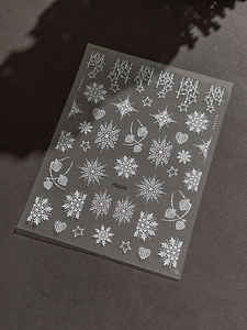 Macro shot of 5D white embossed Christmas snowflake nail stickers with heart and star patterns