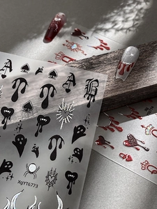 Macro detail of Halloween nail stickers with spiders, ghosts, and blood drops on wood