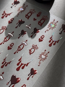 Macro detail of dark red Halloween nail decals with glitter hearts and spider webs