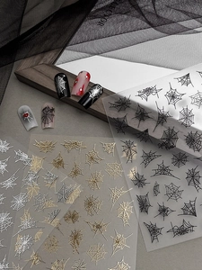 Makroansicht von 3D-Präge-Spinnennetz-Nagelaufklebern in Schwarz, Gold und Silber
