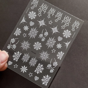 3D embossed white snowflake nail art stickers with heart patterns on dark background