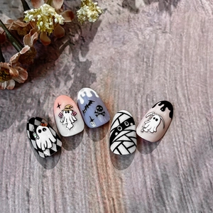 Halloween press-on nails featuring ghosts, mummies, and bat designs on a wood background