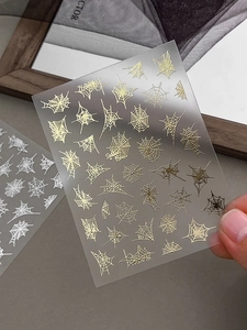 Nahaufnahme von Halloween-Spinnennetz-Nagelstickern mit goldenen Reliefs und 3D-Mustern