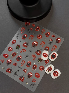 Macro view of Halloween nail stickers with red lips, fangs, and spiders on gray background