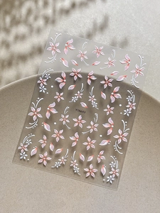 Dettaglio macro di adesivi per unghie 5D in rilievo con petali floreali e motivi a ricciolo