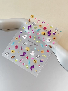Close-up of Halloween nail stickers with ghosts and pumpkins on a grey tray