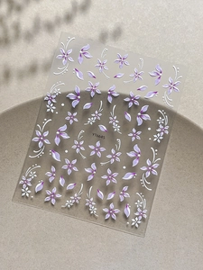 Dettaglio macro di adesivi 3D per unghie con fiori viola e rampicanti bianchi modello YT6645