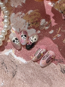 Macro detail of gothic skull and rose embossed nail charms with gold leaf accents