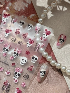 Detailed 5D embossed nail decals featuring white skulls, pink roses, and black bows