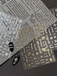 Detailed view of 5D embossed Halloween skull and bone nail stickers in gold and silver