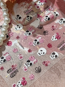 Macro shot of 5D embossed nail decals with skull and rose motifs for gothic nail art design
