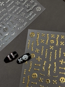 Detailed view of gold and silver Halloween skull nail stickers on black mannequin tips