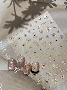Detailed view of gold foil floral nail stickers with cute bow and colorful dot patterns
