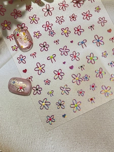 Detail of floral nail stickers with cute bows on pink cat-eye manicured nails