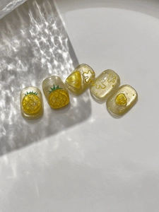 Detail of handmade 3D pineapple nail stickers with yellow glitter and 3D fruit designs