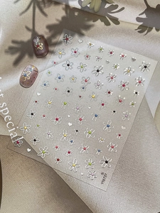 Detailed view of floral and bow nail art stickers with colorful dotted accents on sheet