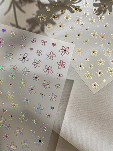 Macro detail of laser and gold foil floral nail stickers with heart and bow motifs
