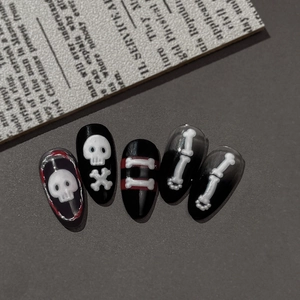 Halloween press-on nails with black base, white skull and bone patterns, and red accents