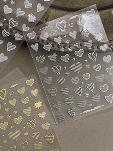 Detailed view of 3D embossed heart nail stickers in metallic gold and silver finish