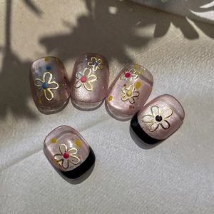 Pink glitter press-on nails with golden flower patterns and colorful dots accent