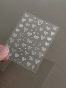 Detail of silver metallic heart embossed nail stickers with linear and dot patterns