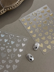 Detail of embossed heart nail art stickers in gold and silver with line patterns