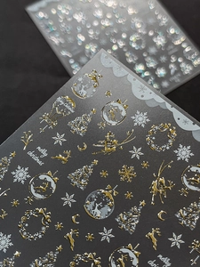 Macro detail of gold and silver Christmas nail art stickers with reindeer and tree motifs