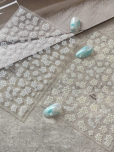 Close-up of white flower nail art stickers with cherry blossom designs and blue nails