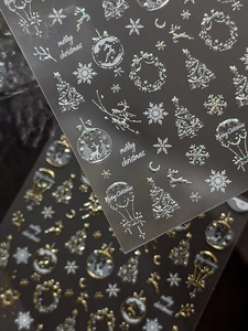 Macro detail of laser gold and silver 3D Christmas nail art stickers with reindeer icons