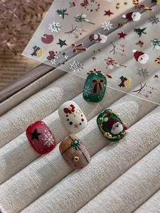 Macro shot of silver-stamped Christmas nail stickers with Santa and snowflake designs