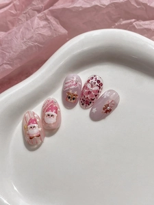 Macro detail of pink Christmas press-on nails with 3D Santa and reindeer designs