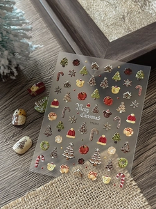 Macro shot of 3D embossed Christmas nail art stickers with gingerbread and snowflake motifs