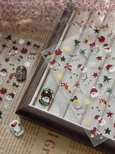Detailed macro view of 3D embossed Christmas nail art stickers with Santa and snowflake motifs