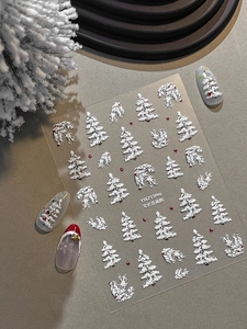 Makro-Detail von 3D-Präge-Nagelstickern mit realistischen Weihnachtsbaum- und Schneemotiven