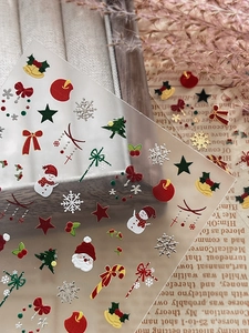 Macro detail of Christmas nail art stickers with Santa and silver snowflake motifs