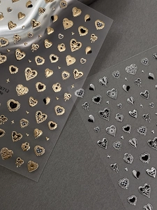 Macro shot of 3D gold and silver heart nail art stickers with metallic texture details