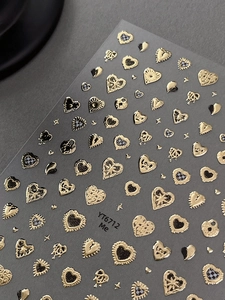 Detail of 3D gold embossed heart nail art stickers with Love text on a dark background