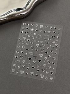 Macro detail of silver heart nail stickers with metallic finish and self-adhesive patterns