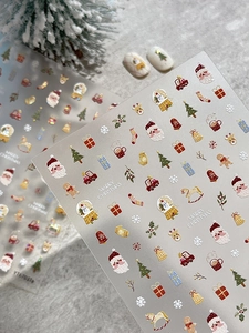 Macro detail of Christmas nail art stickers featuring Santa, snowflakes and embossed patterns